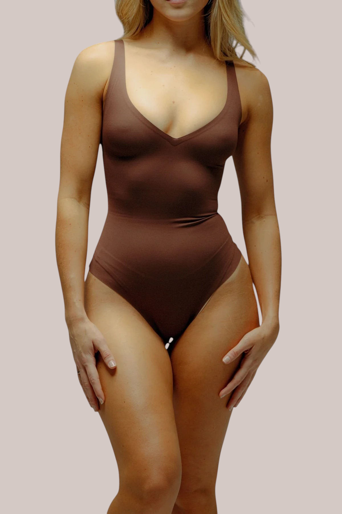 Inshapewear™ seamless sculpting bodysuit in brown with a deep V-neckline and thong-back design on a model.