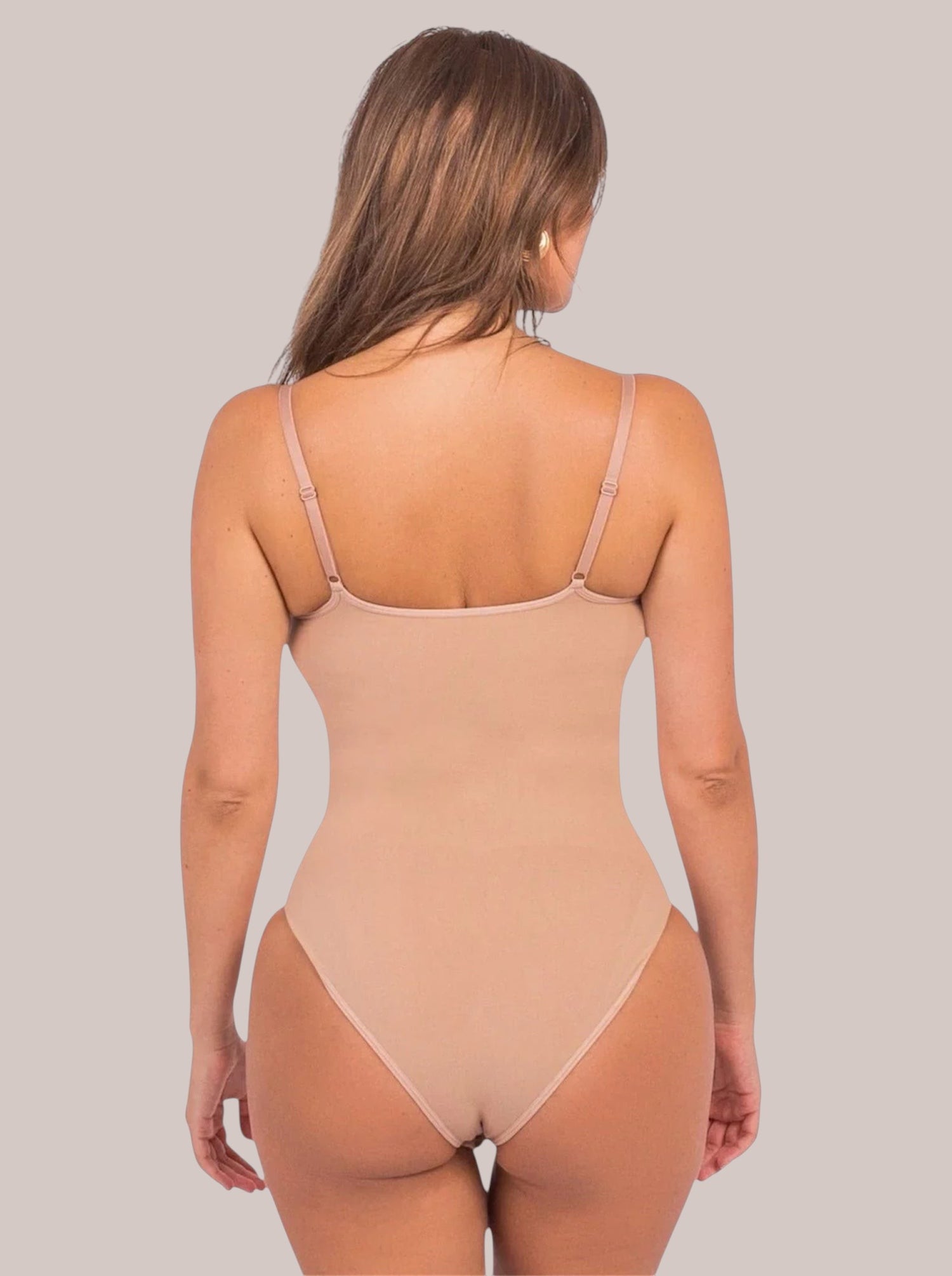 Back view of a woman wearing an Inshapewear™ beige sculpting bodysuit with adjustable straps and seamless design.