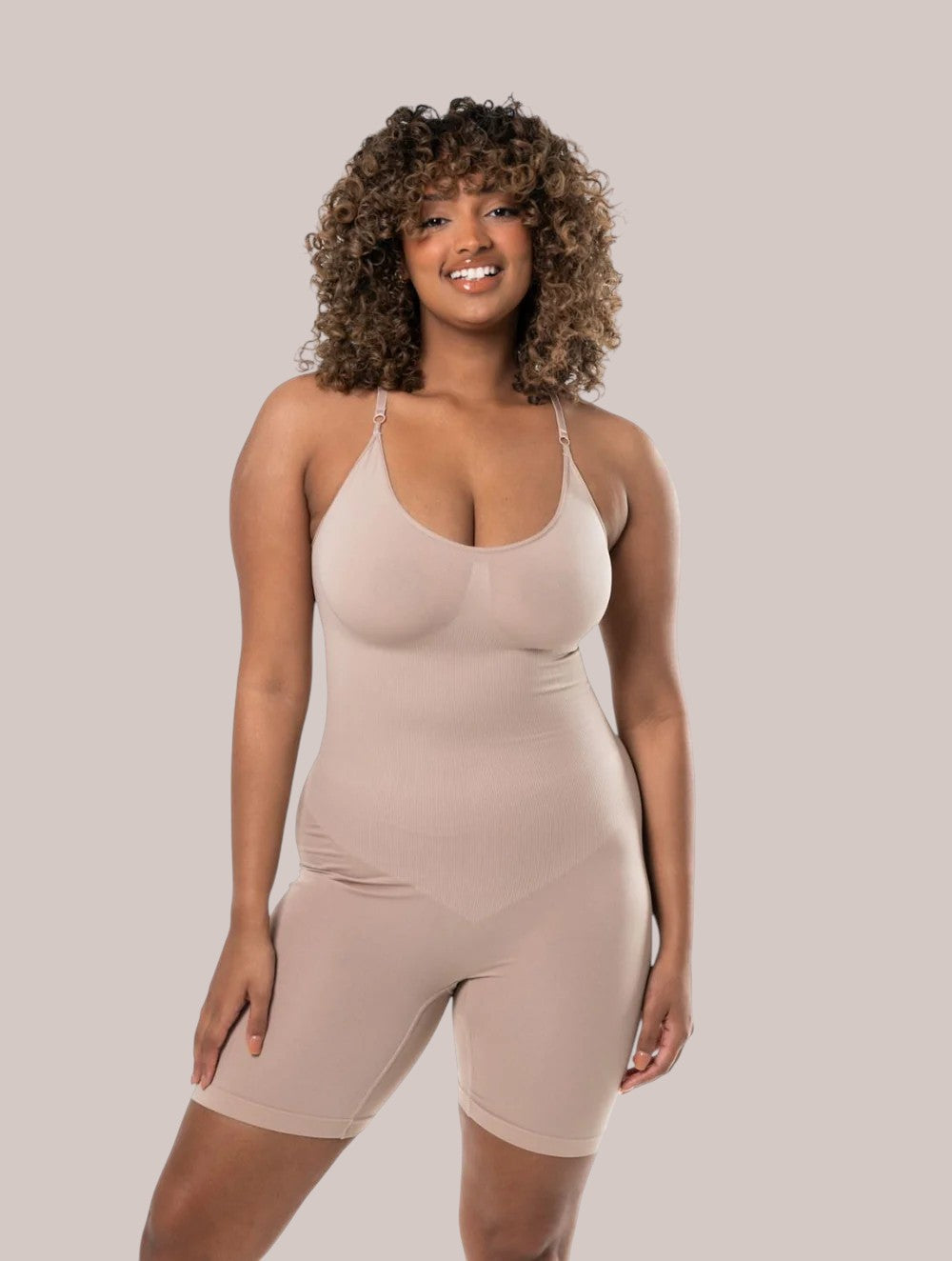 Model wearing a beige Inshapewear™ seamless shaping bodysuit with adjustable straps for a smooth silhouette.