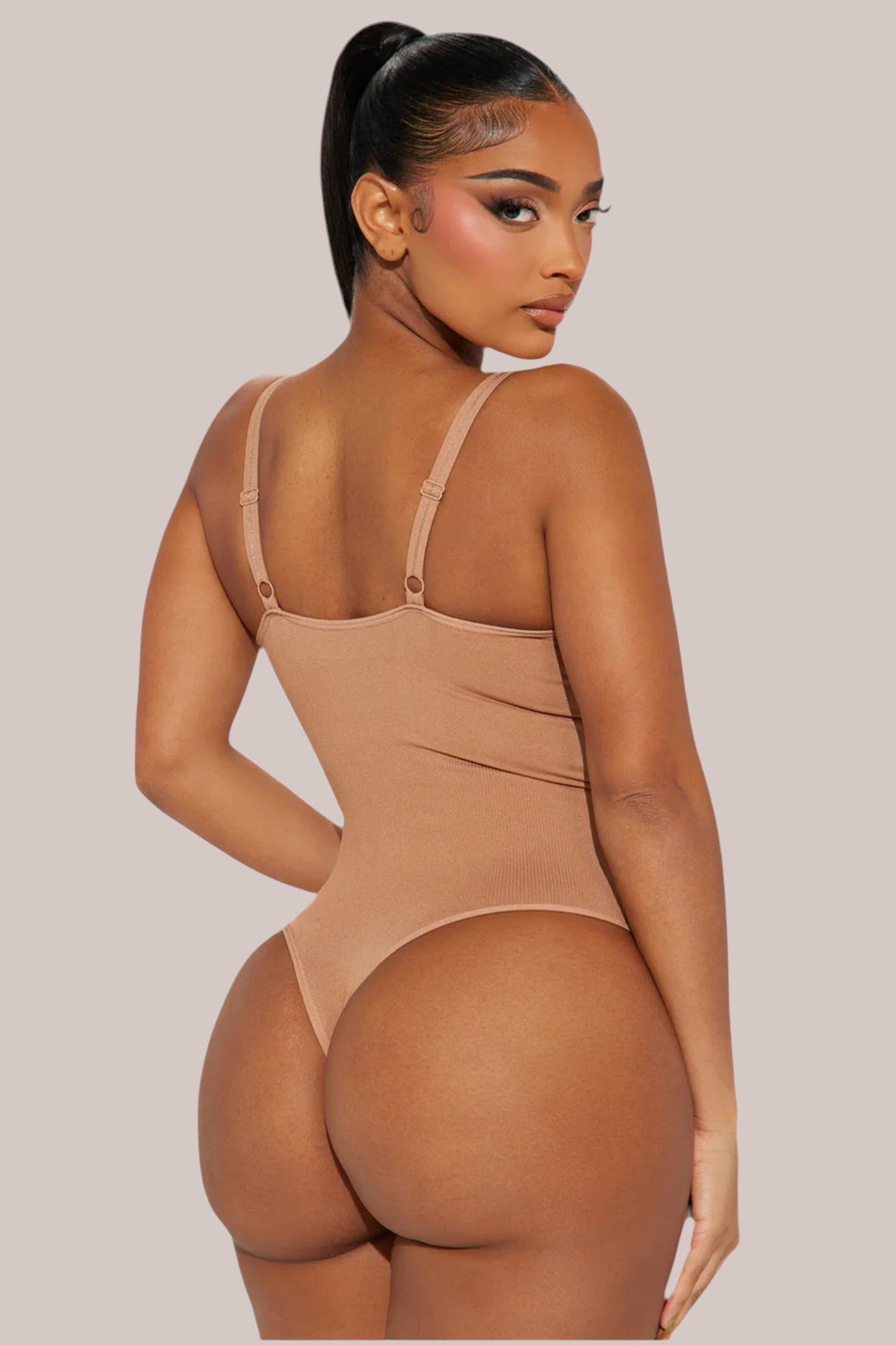 Model wearing a beige Inshapewear™ thong bodysuit that provides targeted compression and a smooth silhouette.