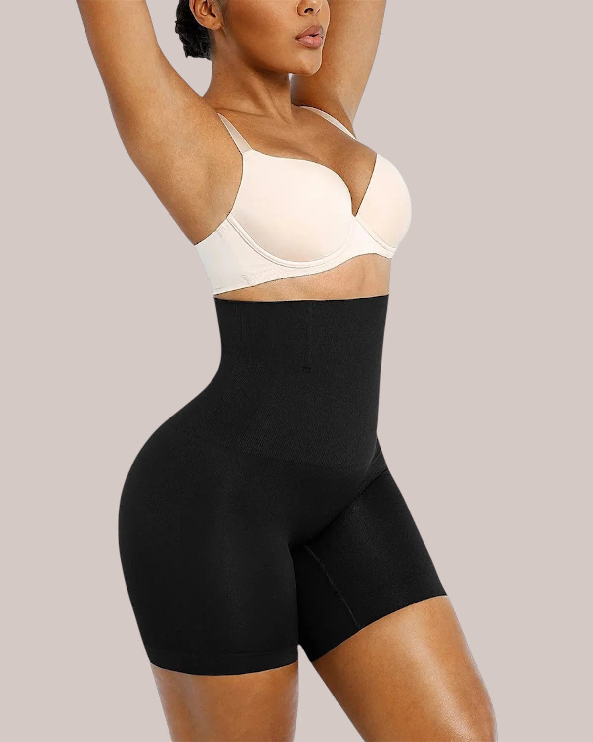 Model wearing Inshapewear™ black high-waisted shaping shorts for a smooth silhouette and tummy control effect.