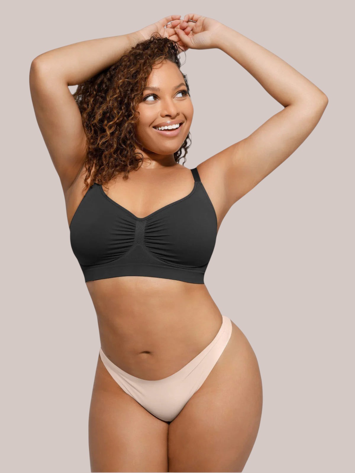 A smiling model wearing a black Inshapewear™ seamless bra with a soft, stretchy design for natural lift and comfort.