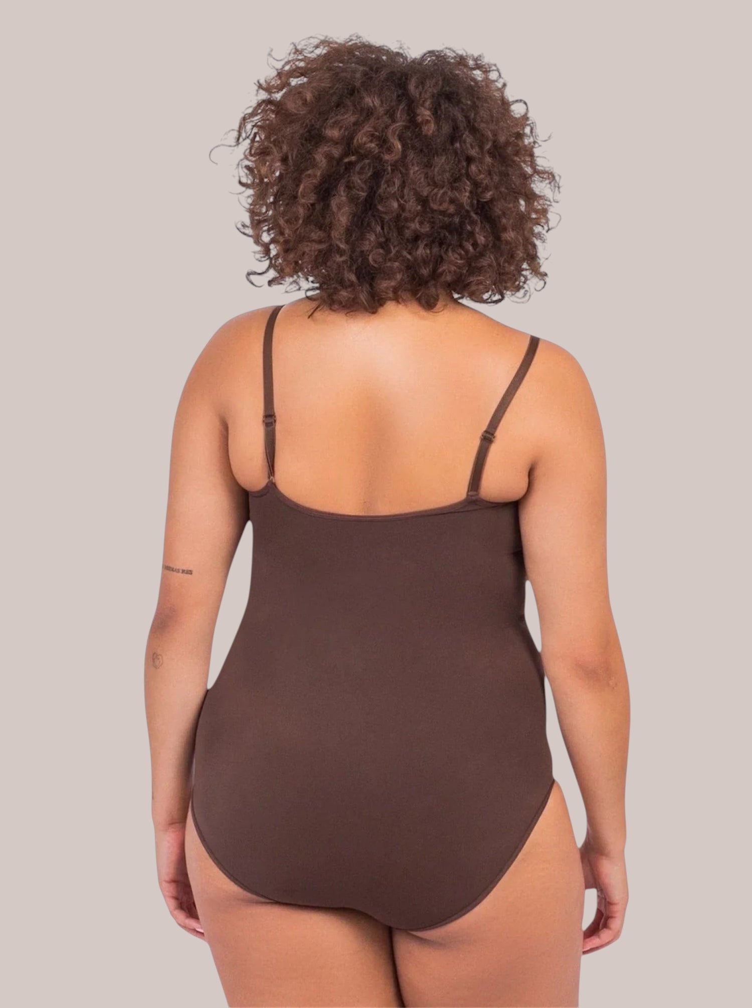 Back view of a woman wearing a brown Inshapewear™ sculpting bodysuit with adjustable straps and breathable fabric.