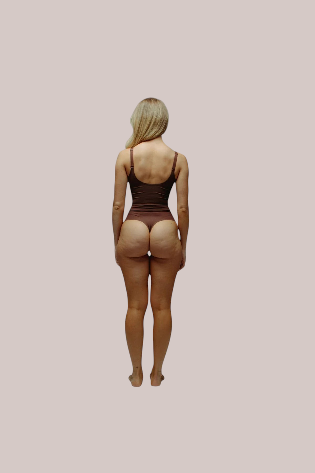 Back view of a model wearing an Inshapewear™ seamless brown sculpting thong bodysuit with adjustable straps.
