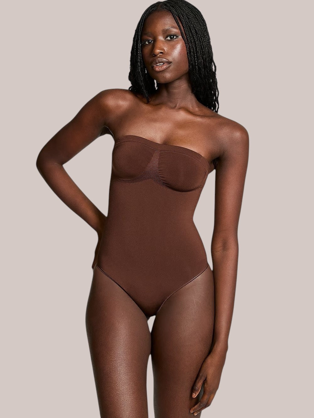 Model wearing a brown Inshapewear™ strapless shaping bodysuit with a smooth, seamless design for a natural silhouette.