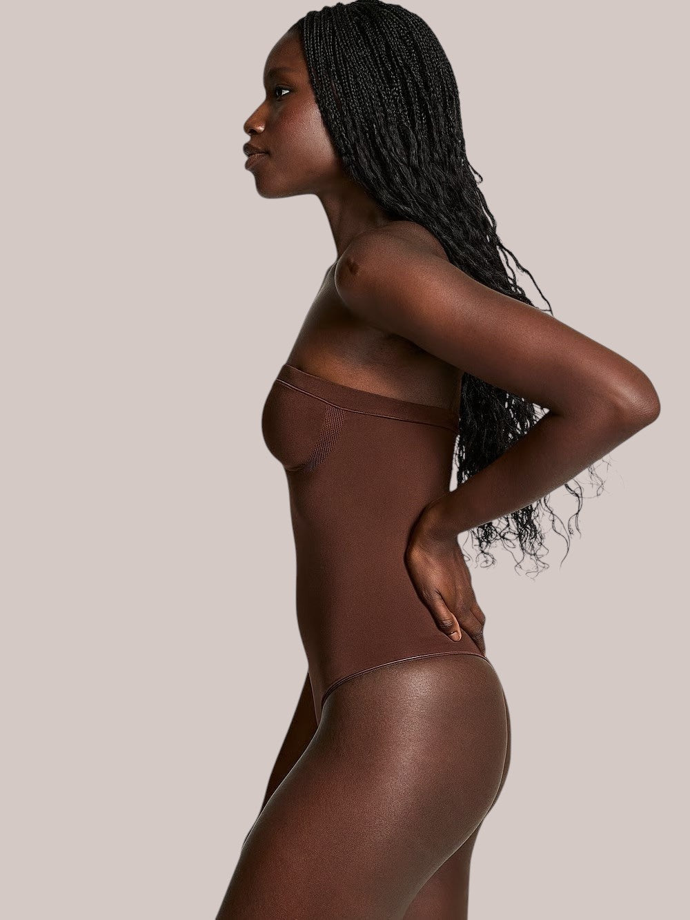 Model wearing a brown Inshapewear™ strapless shaping bodysuit with a smooth, seamless design for a natural silhouette.