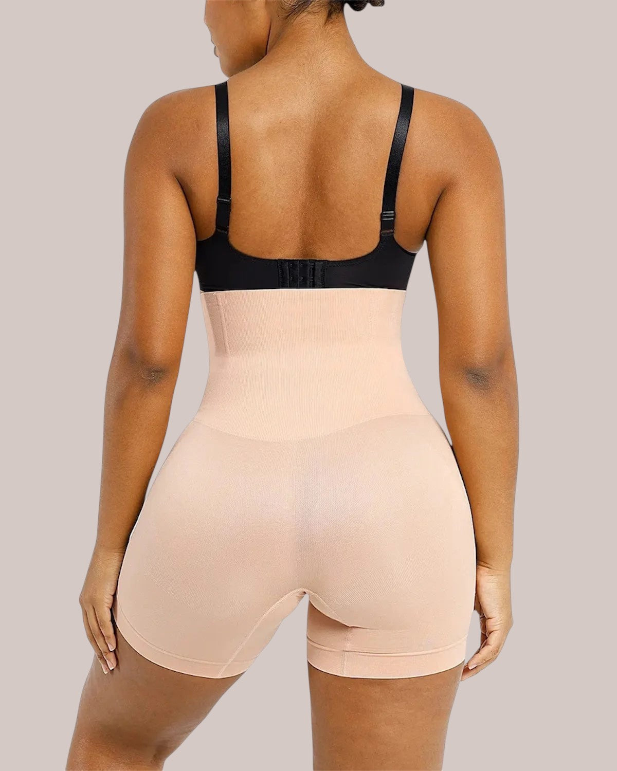 Back view of a model wearing Inshapewear™ high-waisted beige shaping shorts for a smooth silhouette.